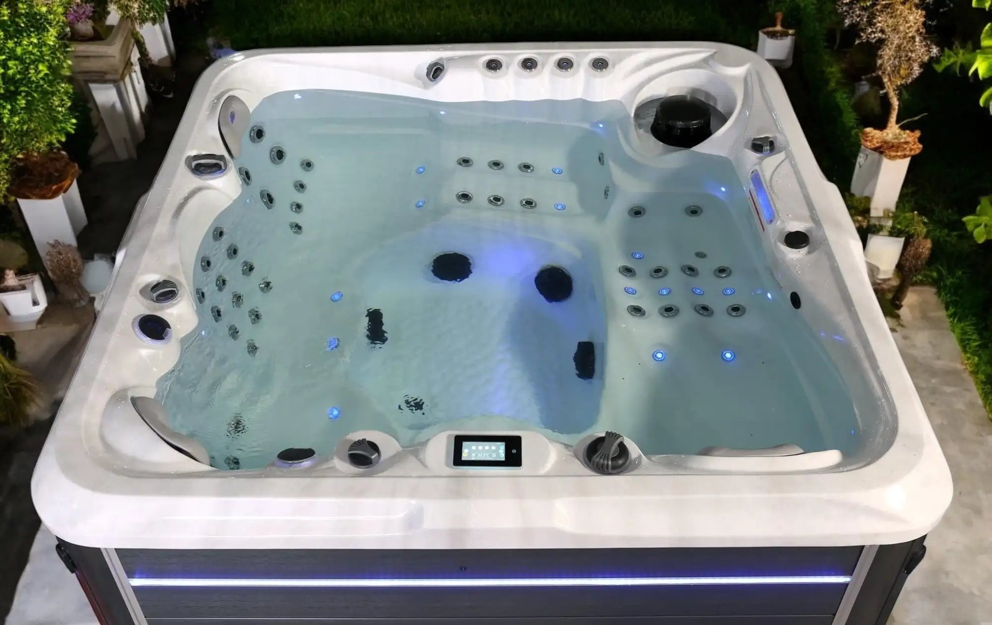 Bain à remous acrylique blanc avec éclairage LED bleu et multiples buses de jets.