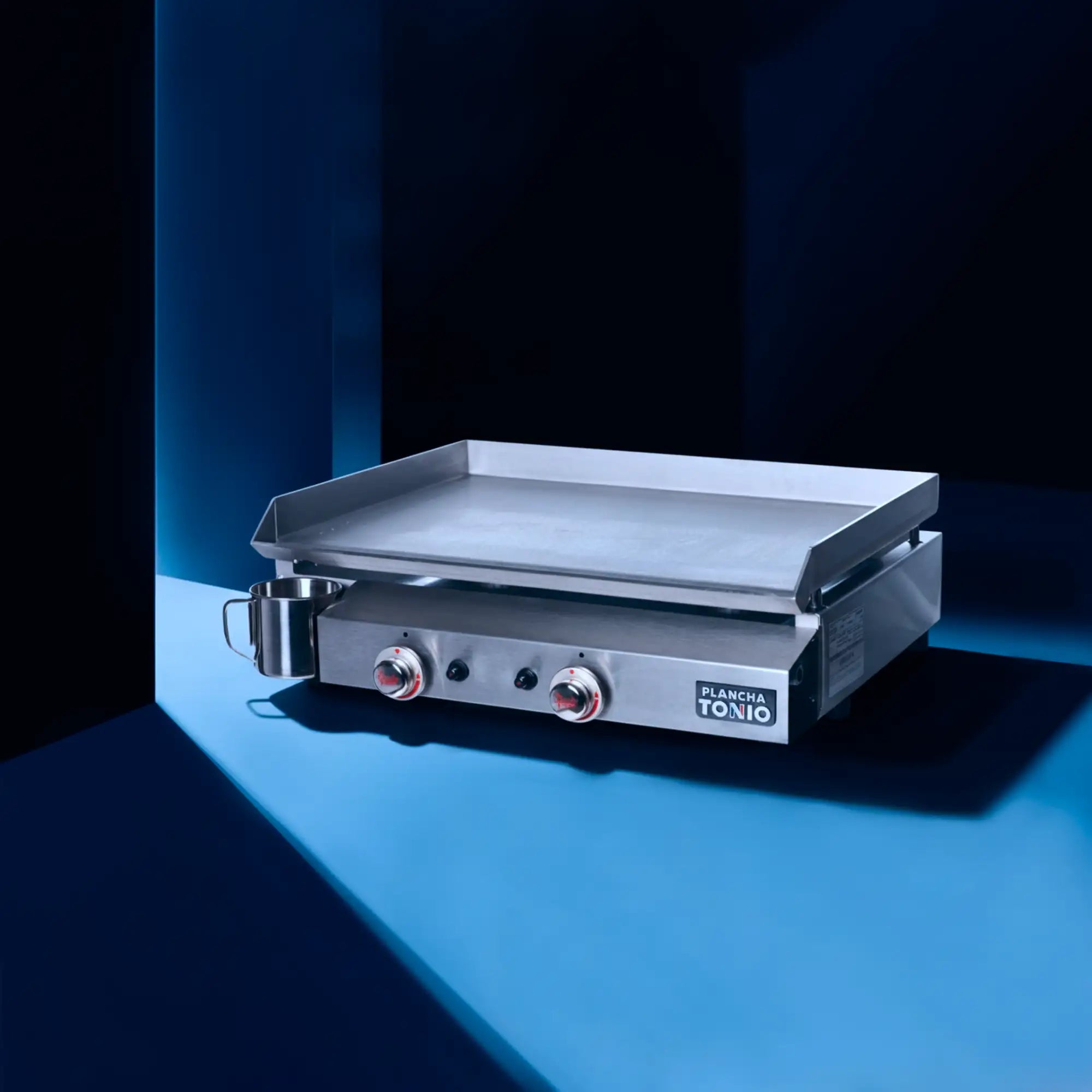 Plaque en acier inoxydable Tonio avec une surface de cuisson plate et rectangulaire et deux boutons de commande accentués en rouge.